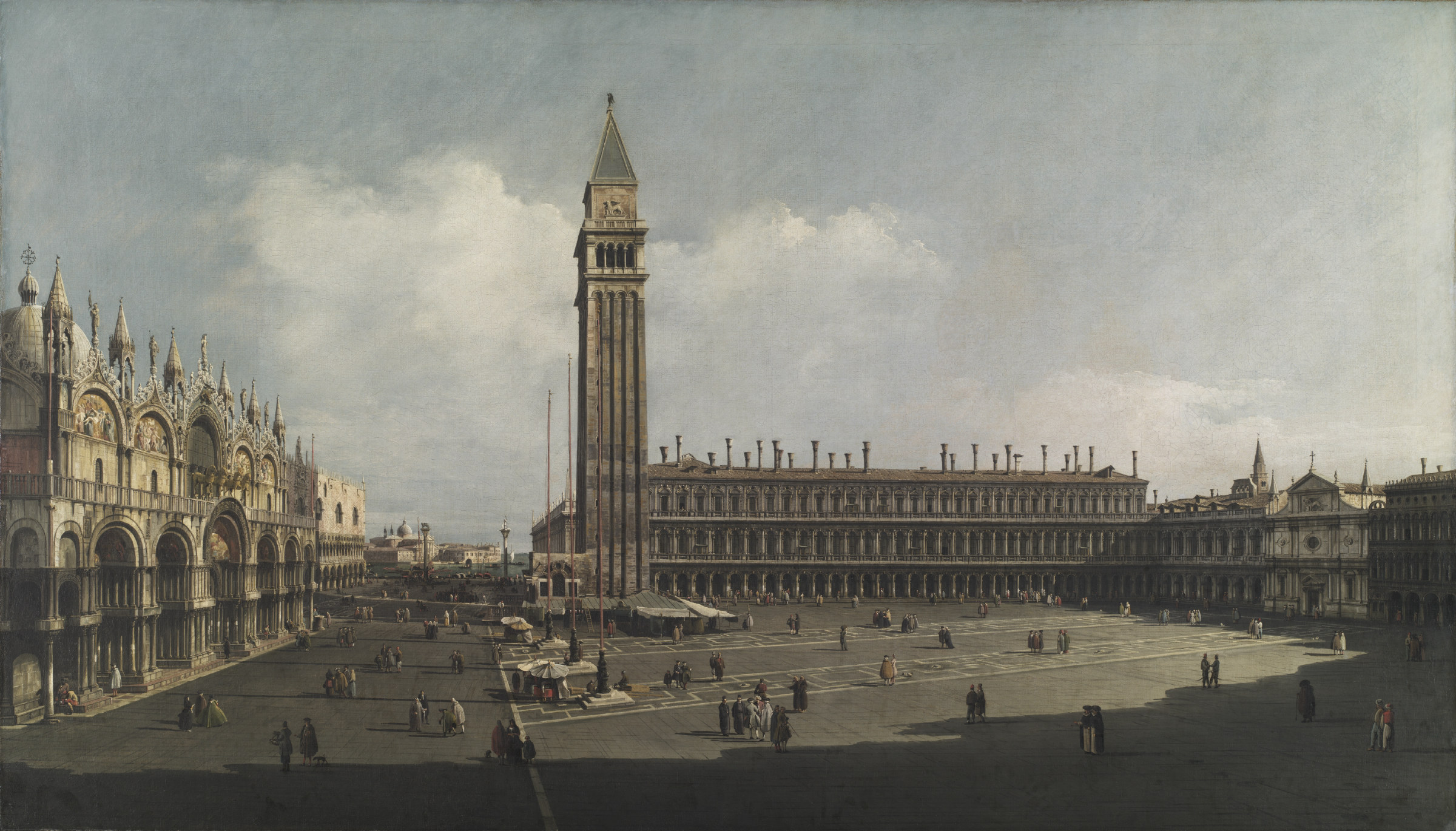 A wide view across the Piazza San Marco in Venice: the basilica's domes and the campanile rise beyond the arcaded square, where small groups of figures cast crisp shadows in bright sunlight.