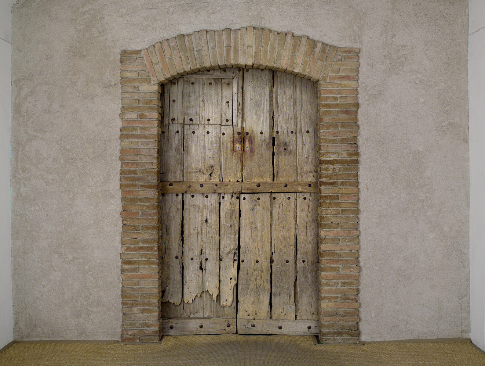 Marcel Duchamp, Étant donnés: a weathered wooden door set in a brick arch in a plaster wall