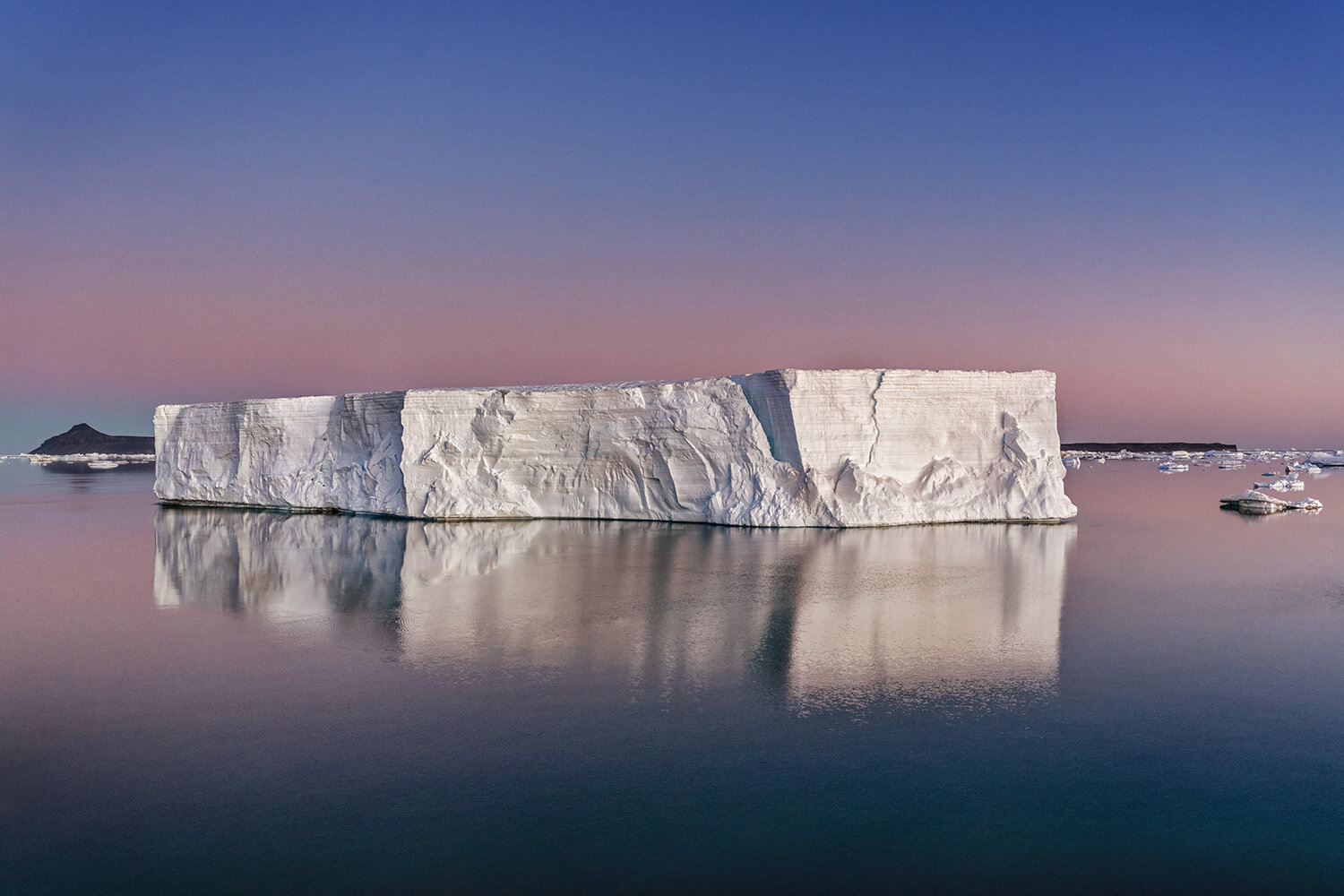 Cristina Mittermeier, Violet Sunset, 2022: a flat-topped iceberg reflected in still water under a violet sky, Antarctica