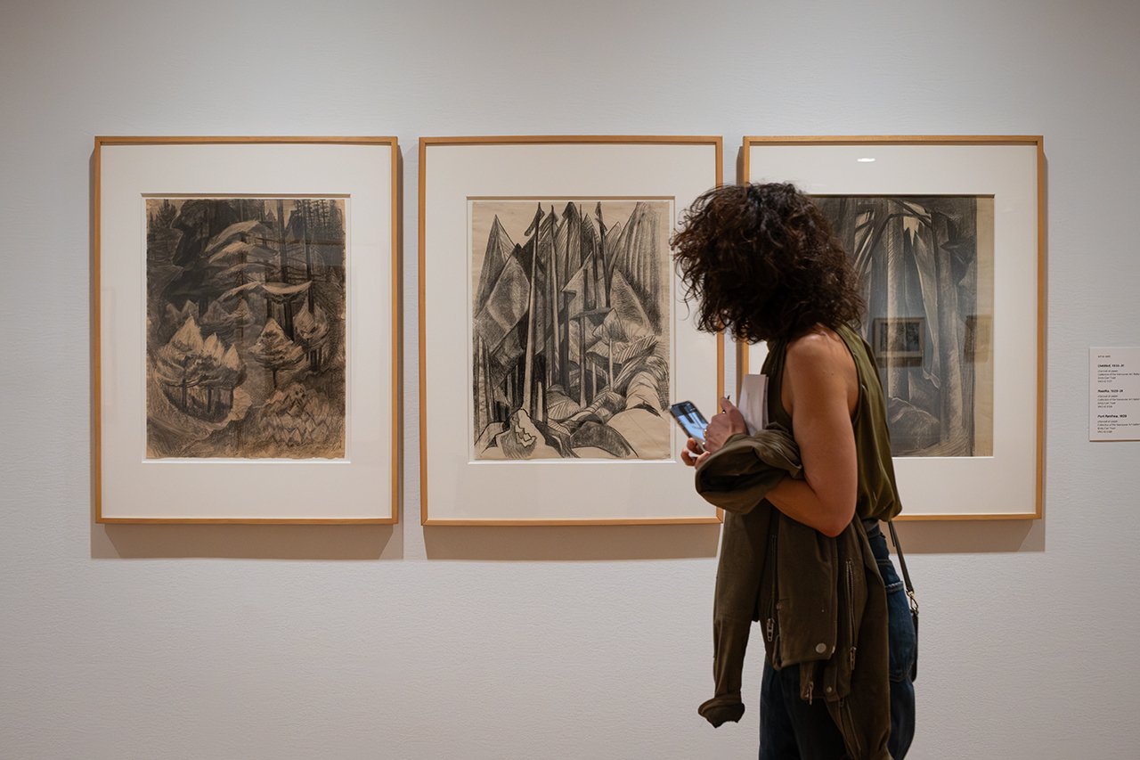 A visitor views three Emily Carr forest drawings in That Green Ideal