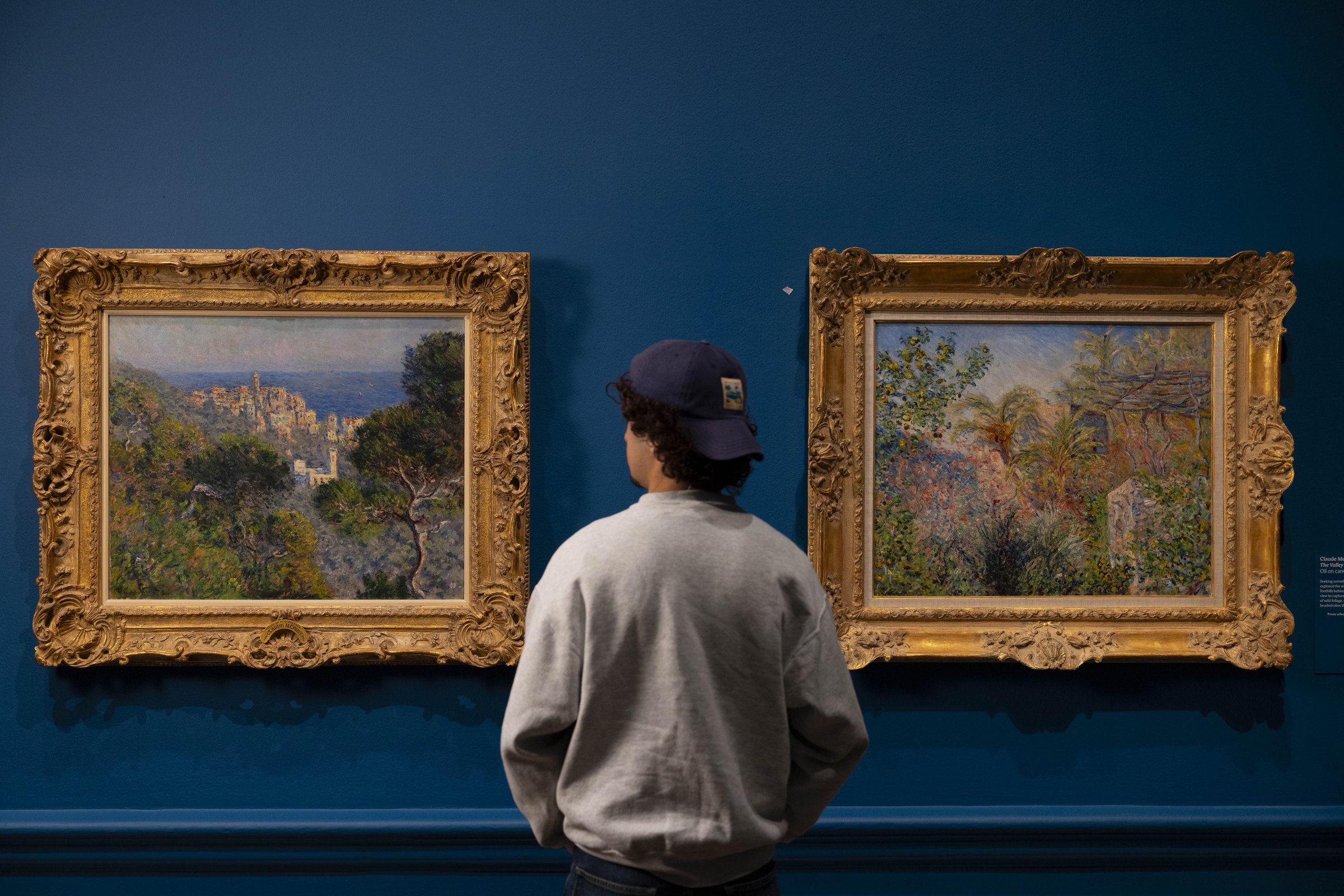 Painting the French Riviera at the Royal Academy of Arts, London: a visitor standing between two Riviera landscape paintings
