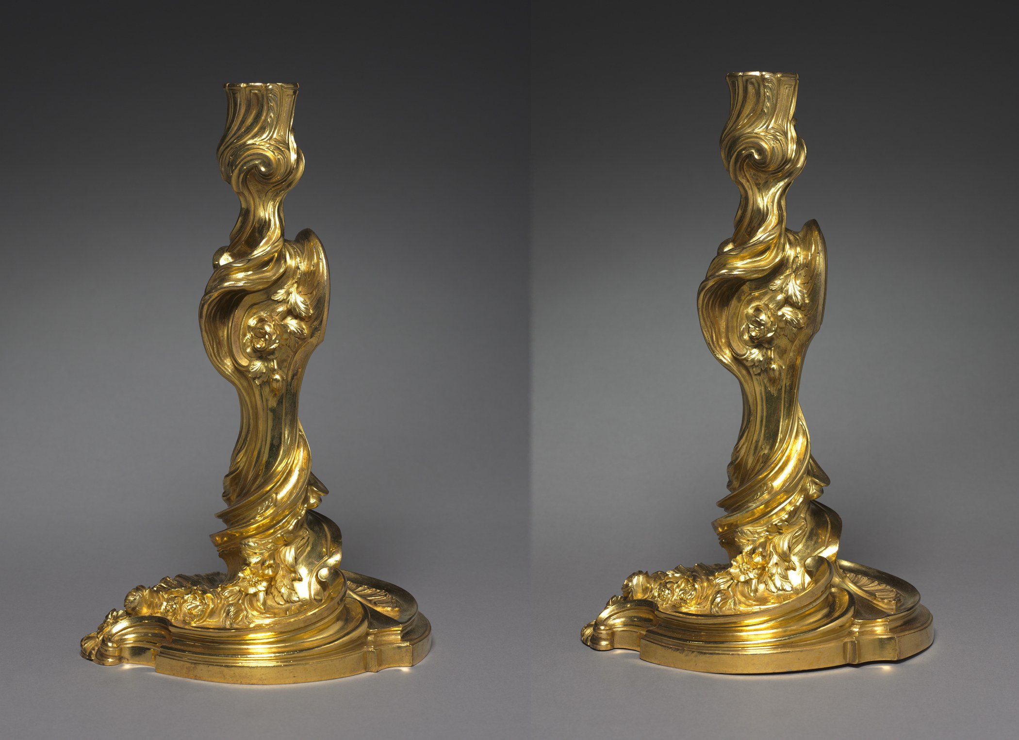 Pair of twisting gilt-metal Rococo candlesticks shown side by side
