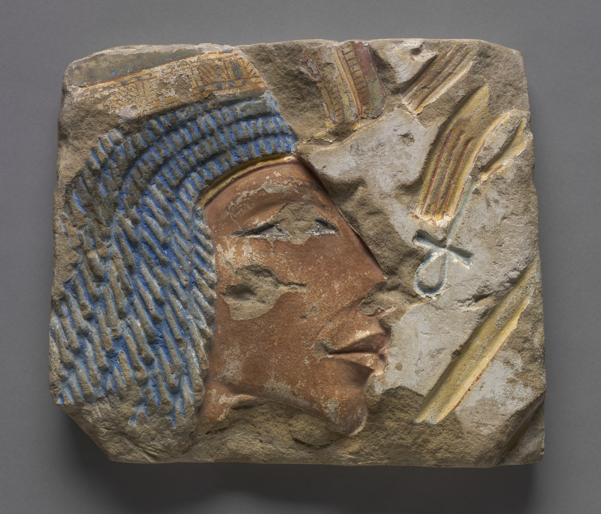 A carved sandstone talatat block bearing a profile relief portrait of Queen Nefertiti, her long neck and angular chin rendered in the elongated Amarna style.