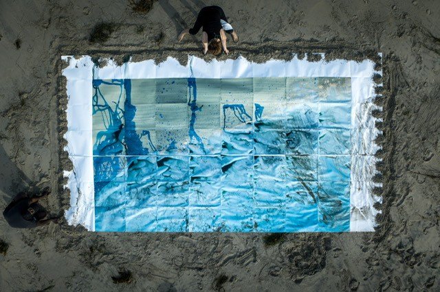 Meghann Riepenhoff adding mushroom ink to a large cyanotype grid laid on the ground, seen from above