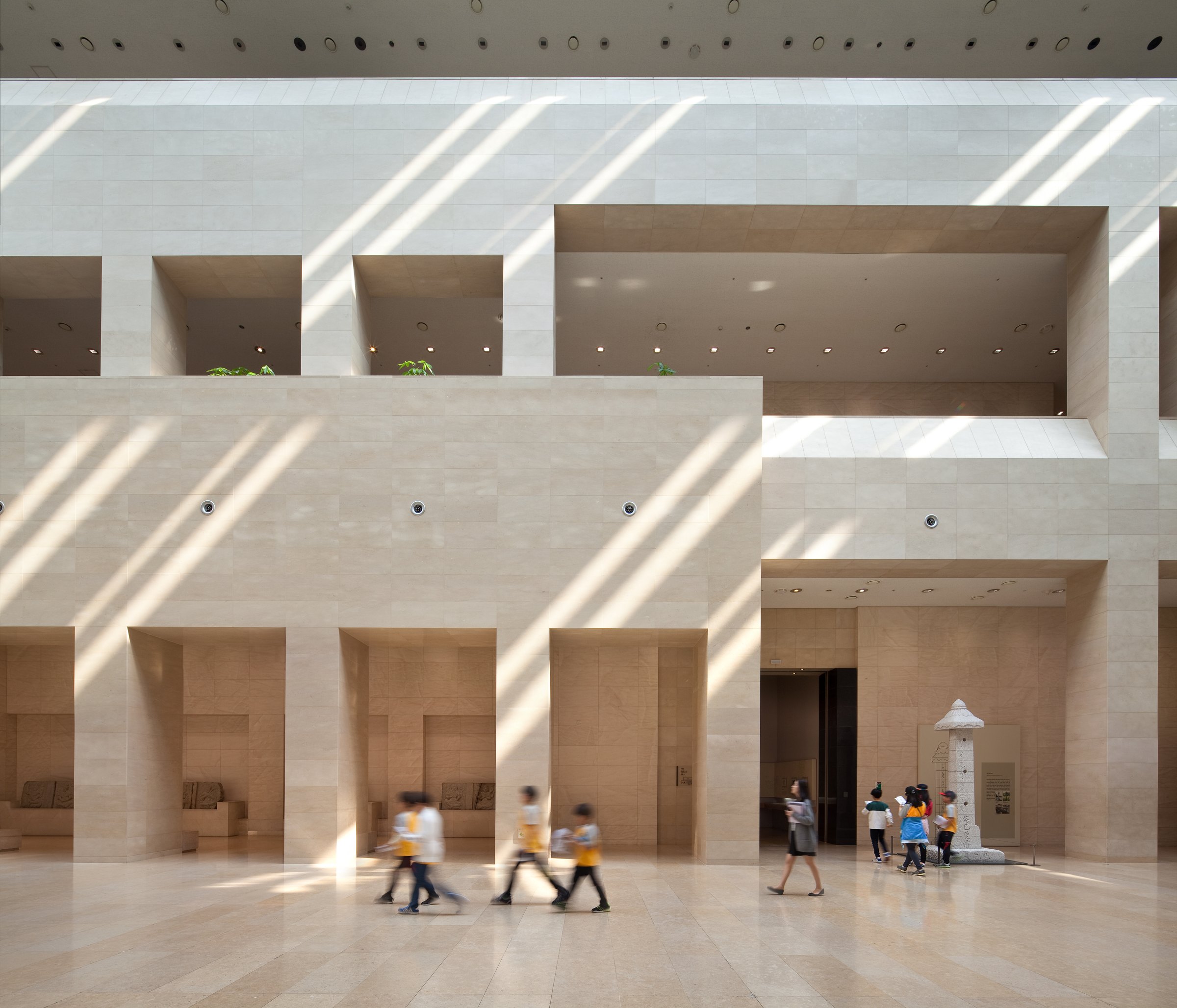 The National Museum of Korea’s Path to History, a tall pale-stone hall with sunlight falling in diagonal bands and a stone pagoda at the far end