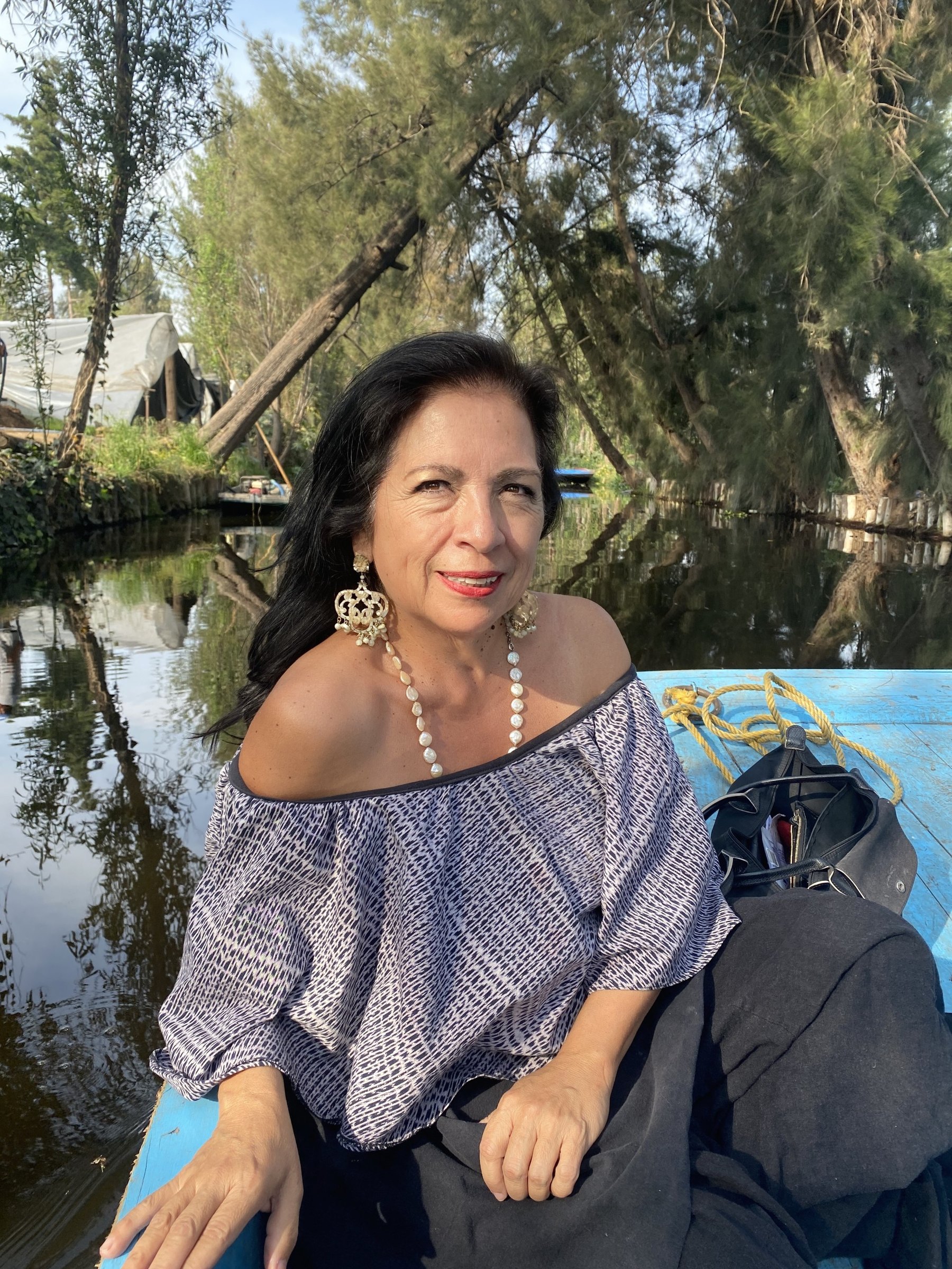 Portrait of the artist Betsabeé Romero seated outdoors by the water