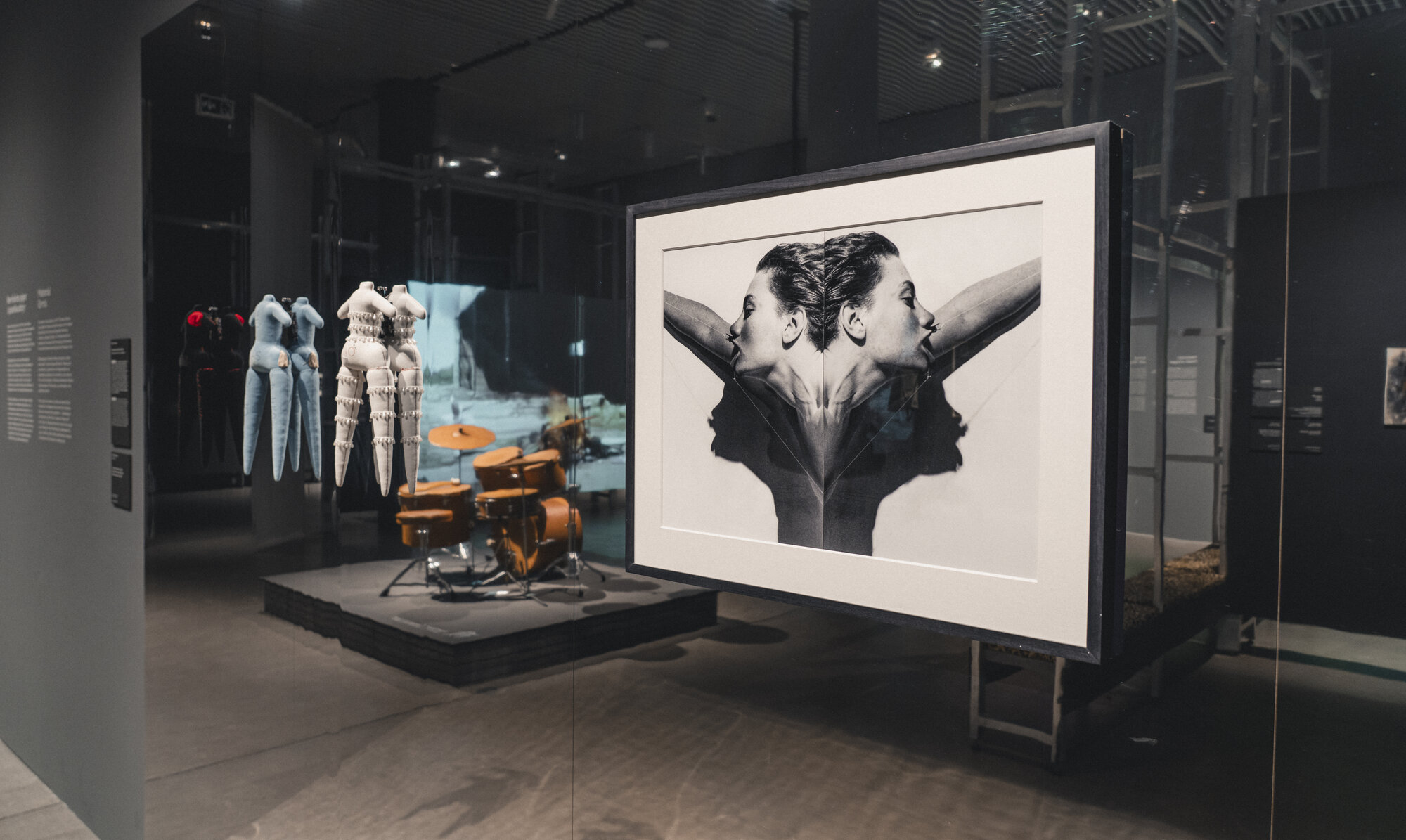Installation view of "UNRULY: The Body in Punk" at ARoS, a large printed graphic beside a display of punk clothing