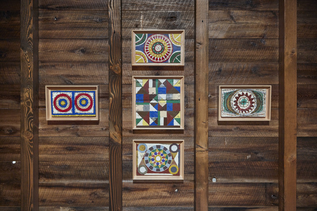 Emery Blagdon painted panels with radiating geometric patterns mounted on a weathered wood wall
