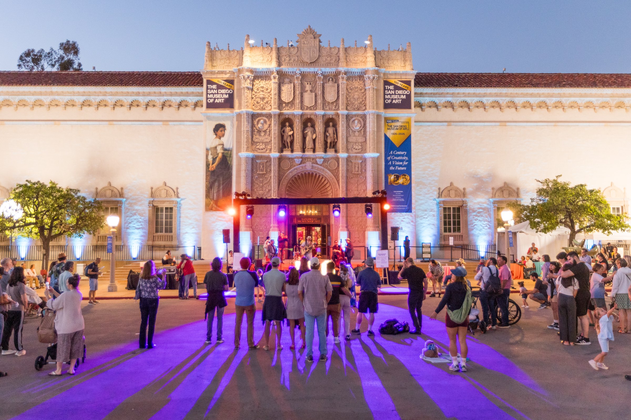 The museum’s façade lit for an evening event, with a crowd in the plaza