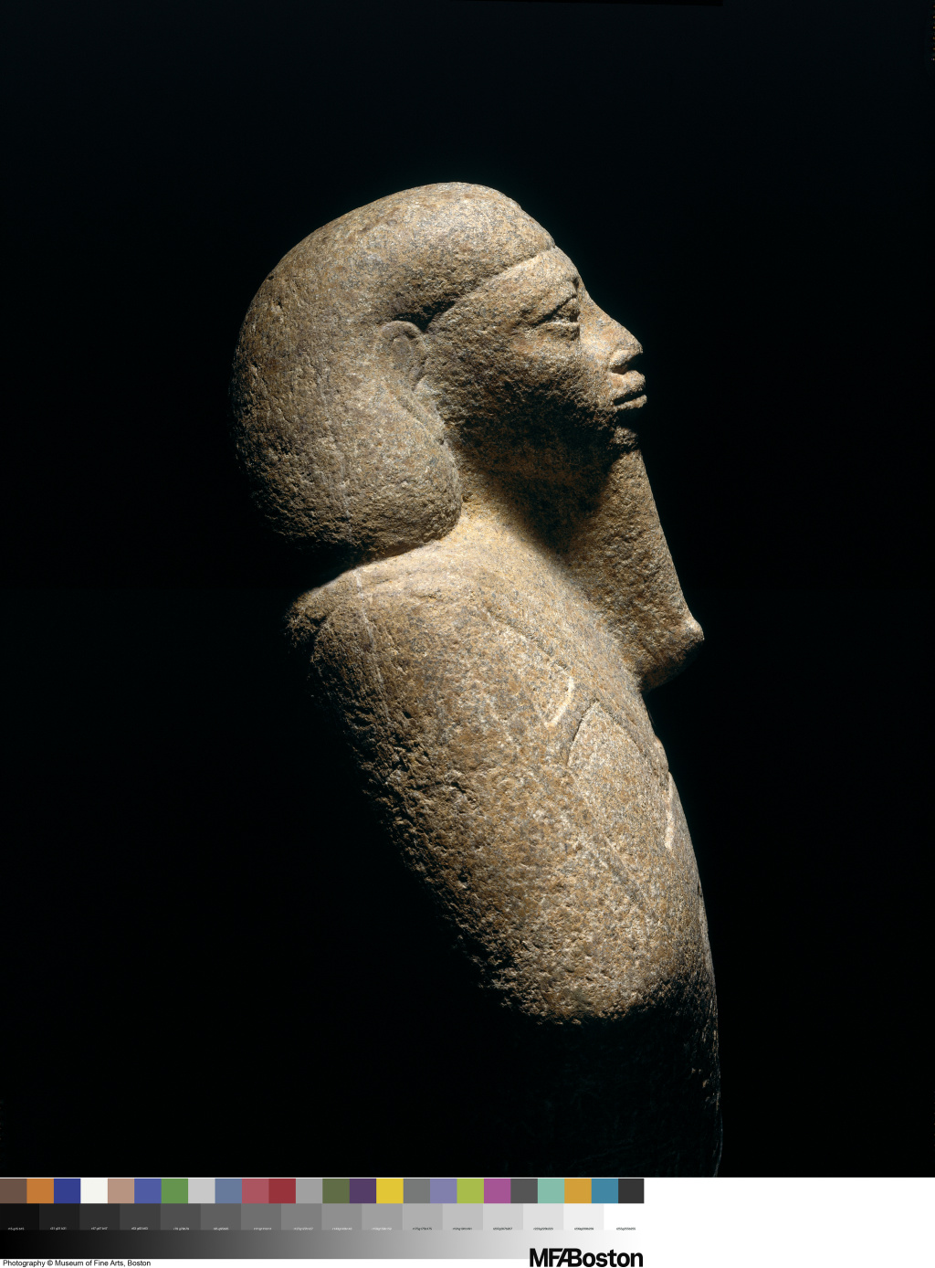 Sculpture of a person’s head and chest seen in profile. The person wears a smooth headdress and long, stylized beard.