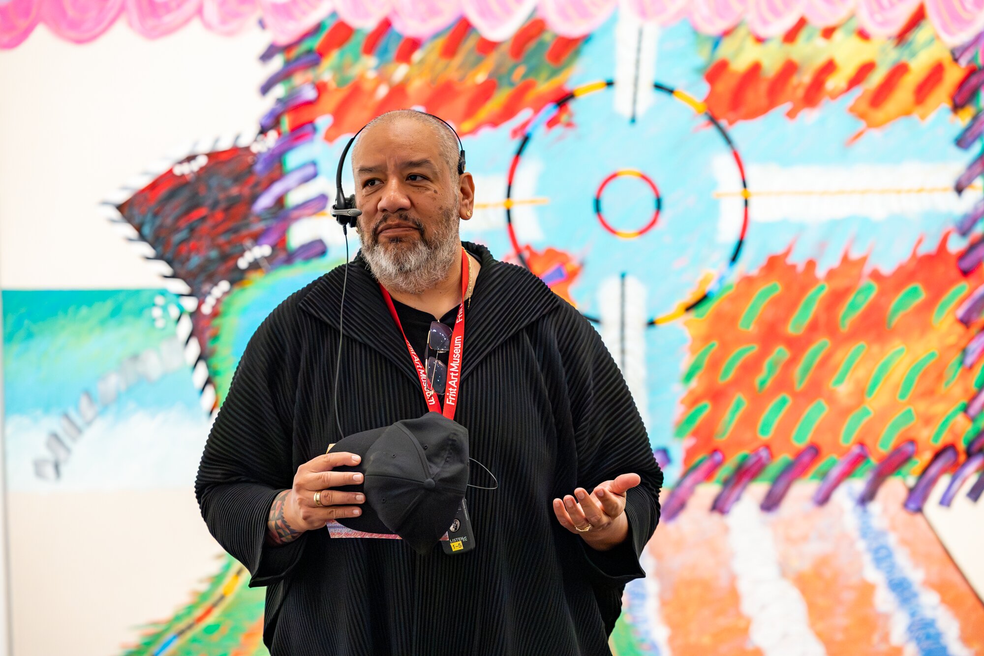 A museum educator speaking in front of a colorful mixed-media work in "An Indigenous Present" at the Frist Art Museum
