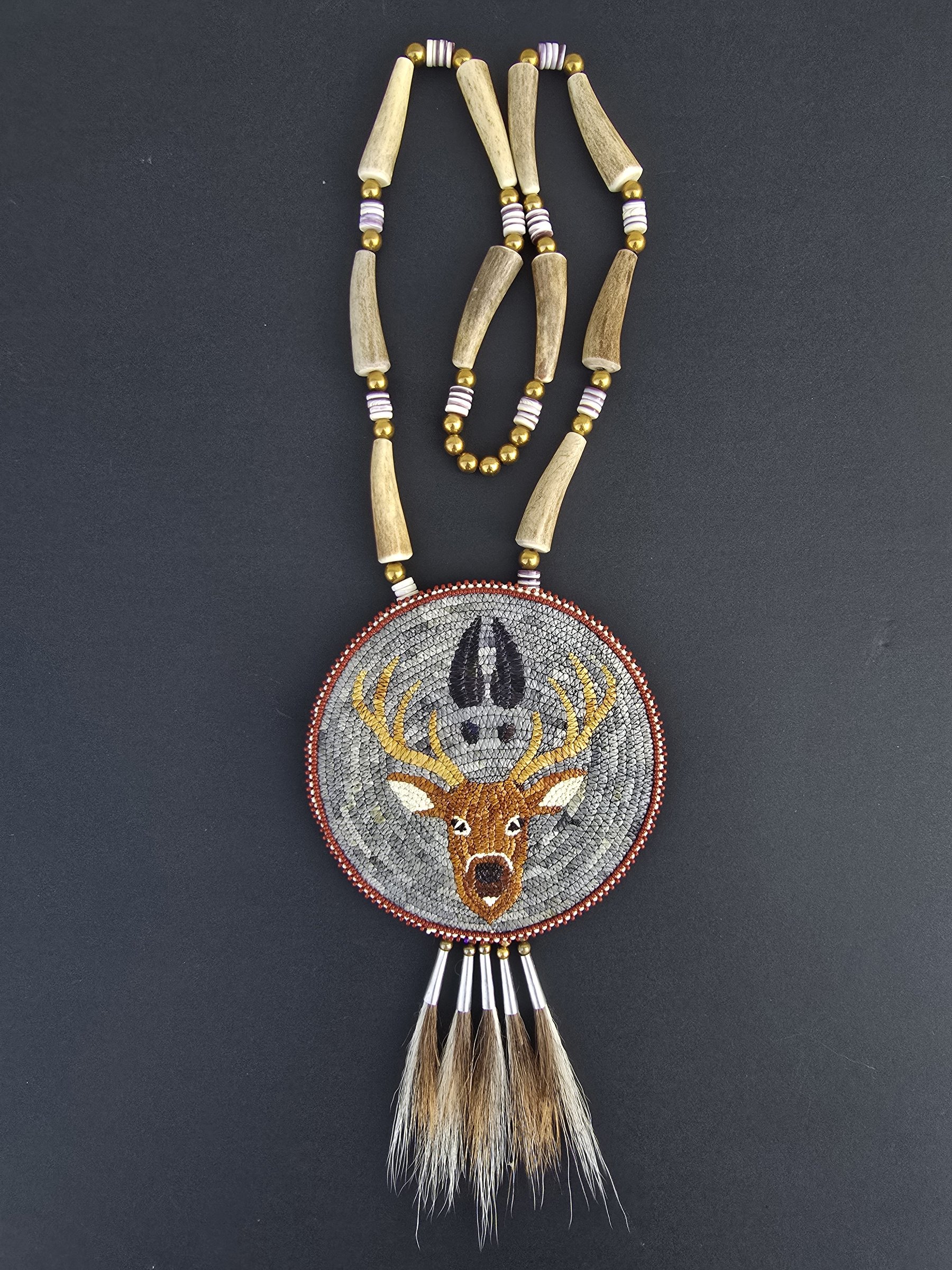 Beaded necklace of quills and antler with a round medallion showing a deer head