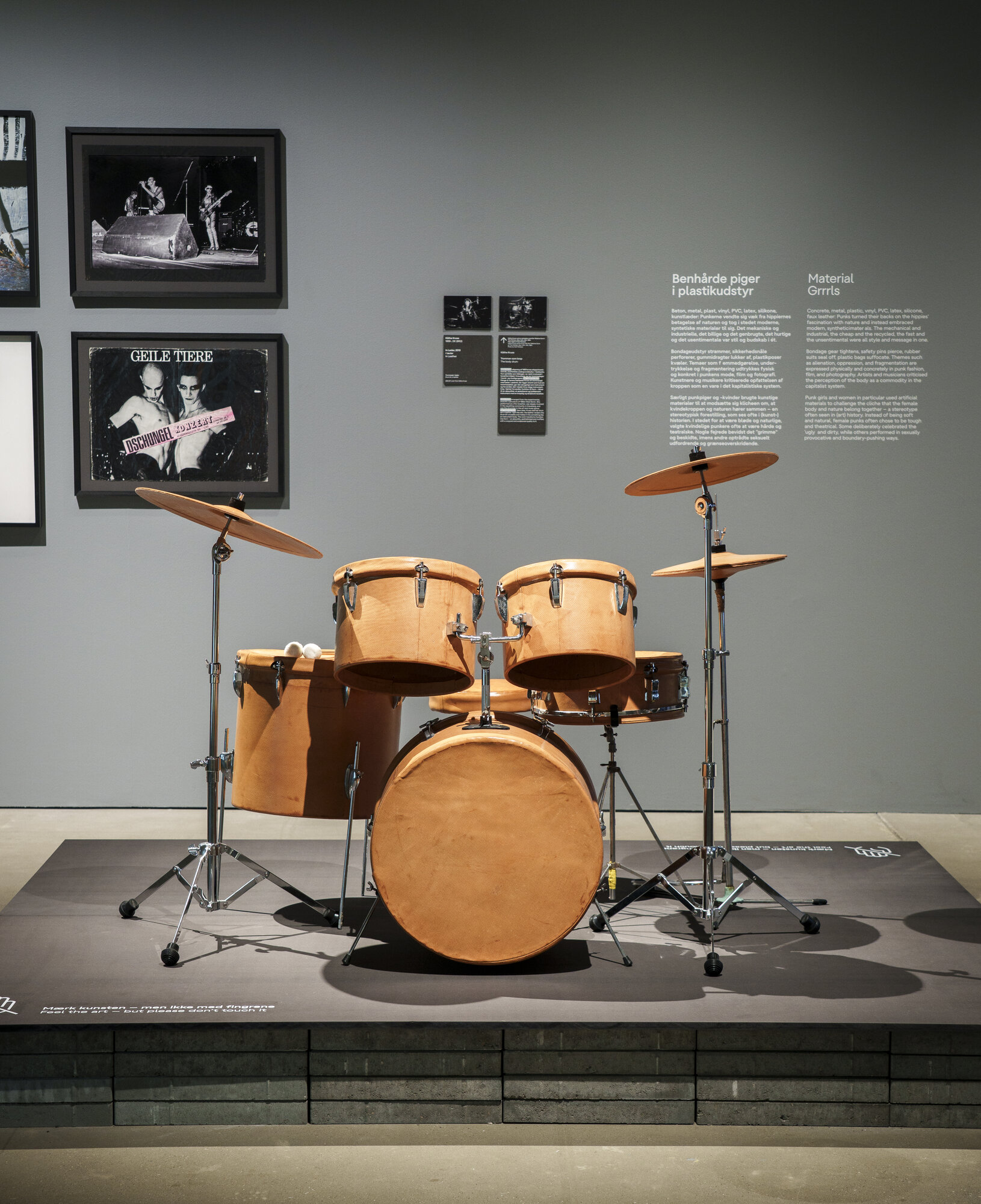 Installation view of "UNRULY: The Body in Punk" at ARoS, a drum kit displayed on a gallery plinth