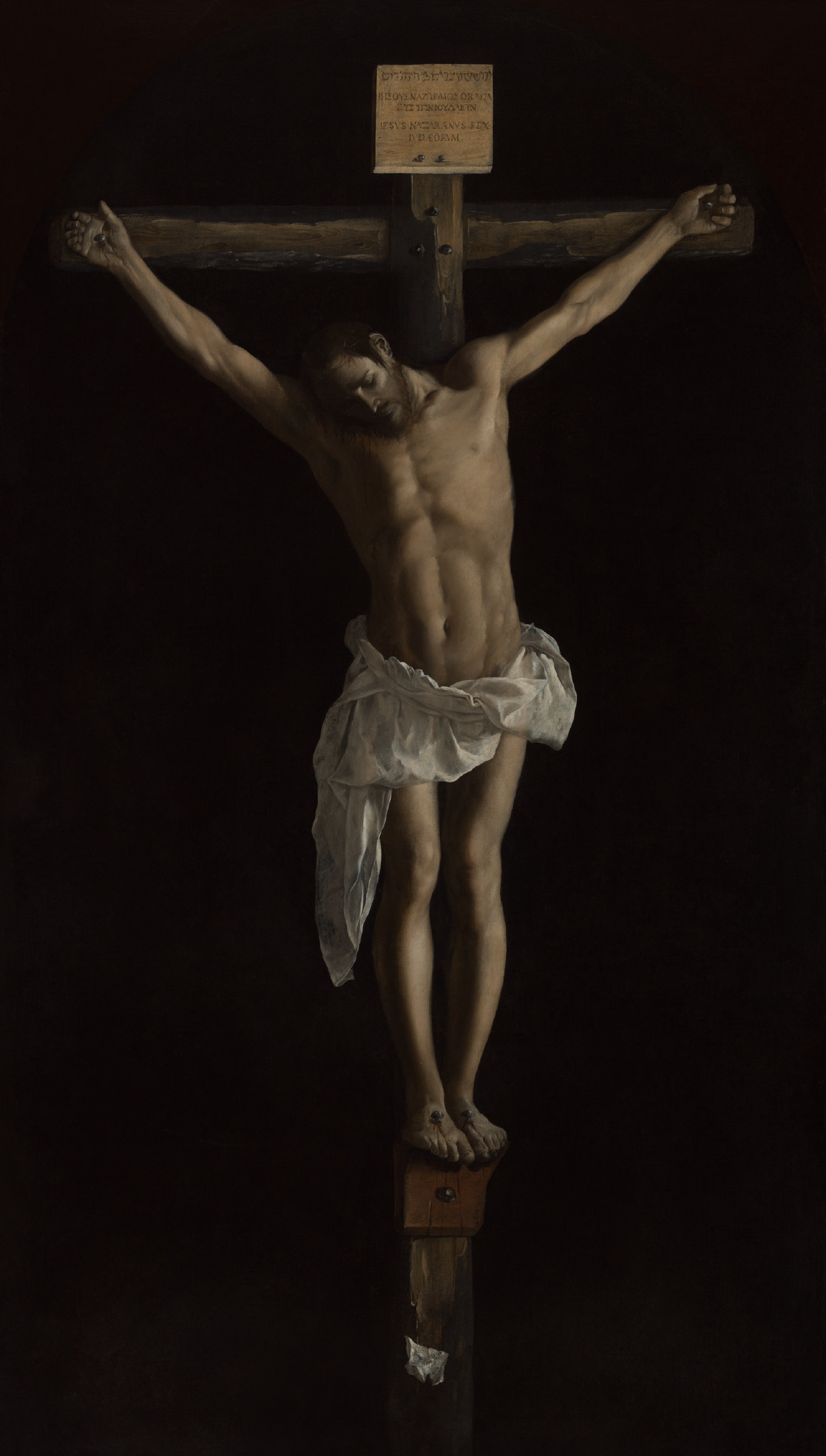 A life-size crucified Christ emerging from deep blackness, his pale body lit from the left, head fallen to one side, the white loincloth the brightest note in the painting.