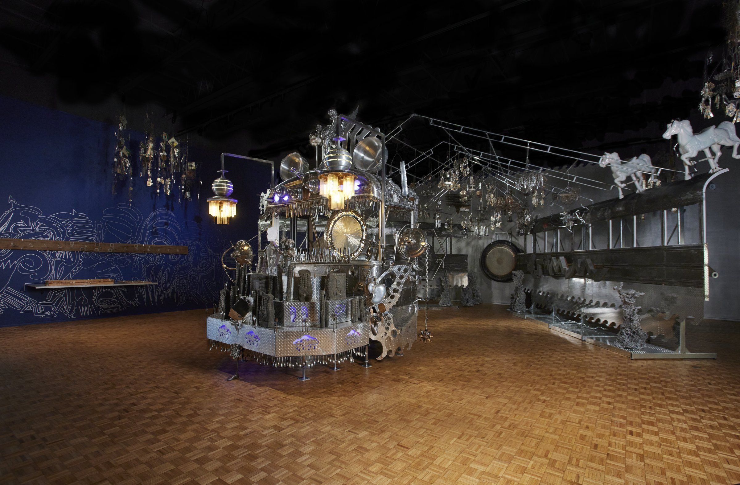Guadalupe Maravilla’s sculptural altar and Emery Blagdon’s hanging metal components in a dark blue gallery
