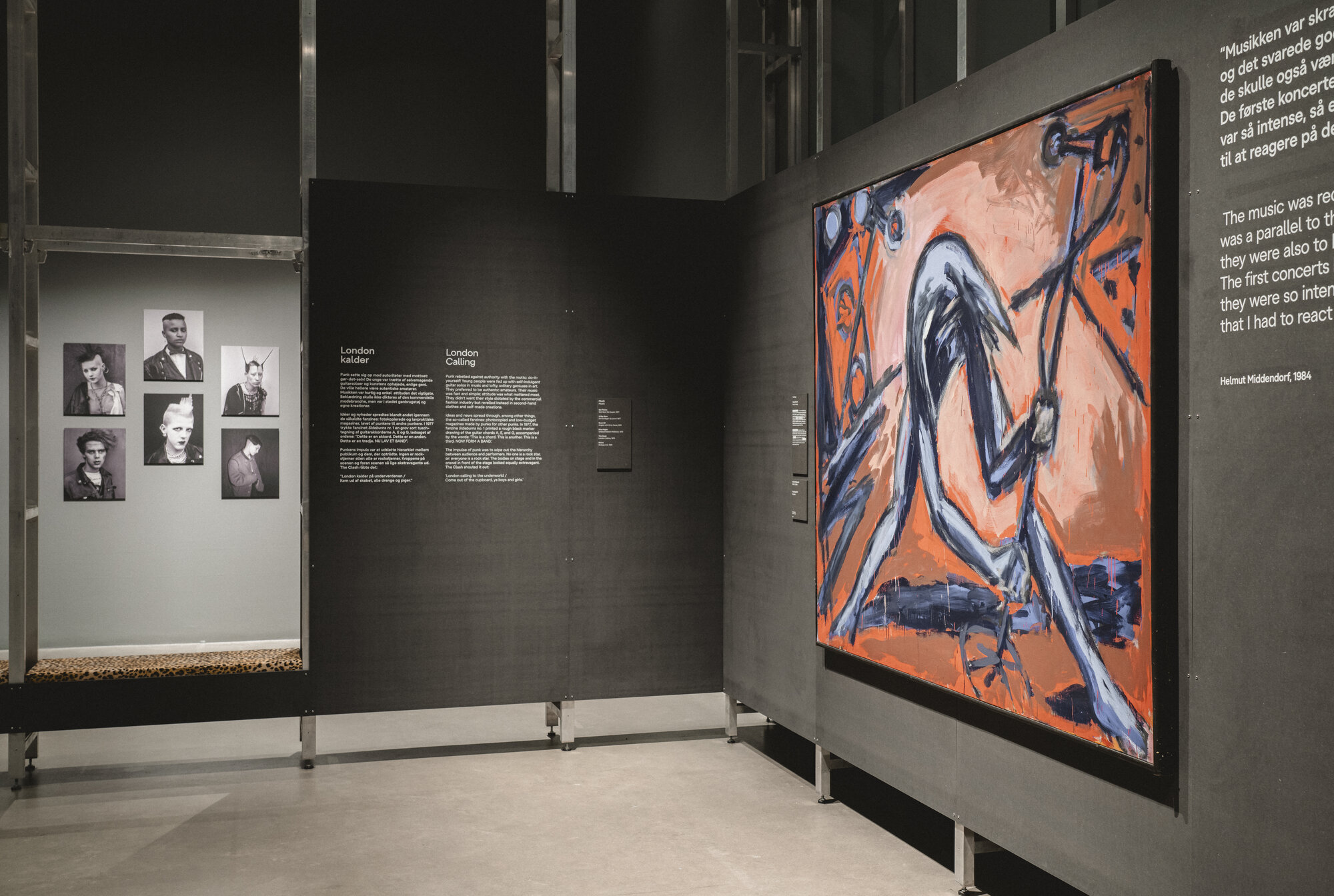 Installation view of "UNRULY: The Body in Punk" at ARoS, a large blue swirling graphic artwork on the gallery wall