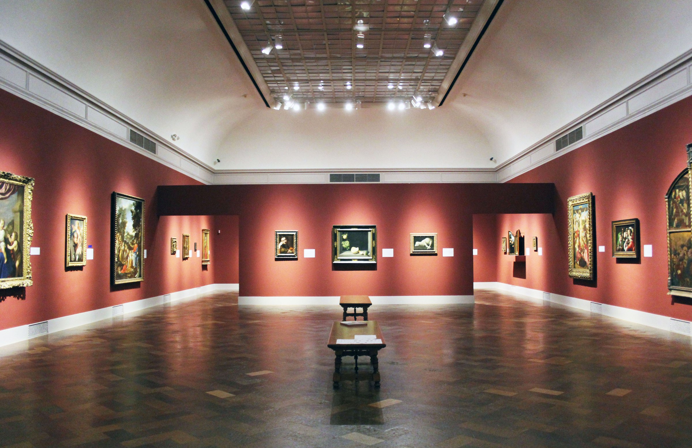 A red-walled gallery hung with European paintings