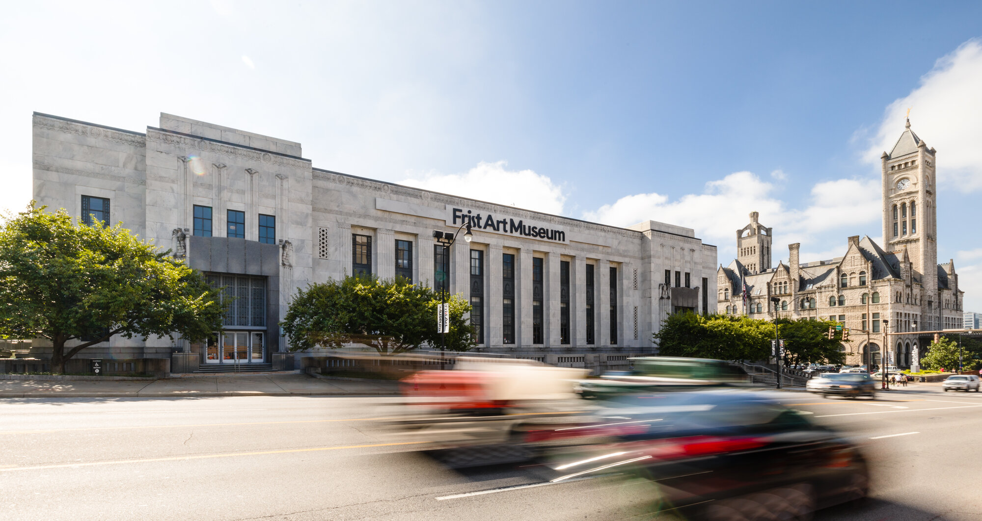 Street view of the Frist Art Museum building with passing traffic
