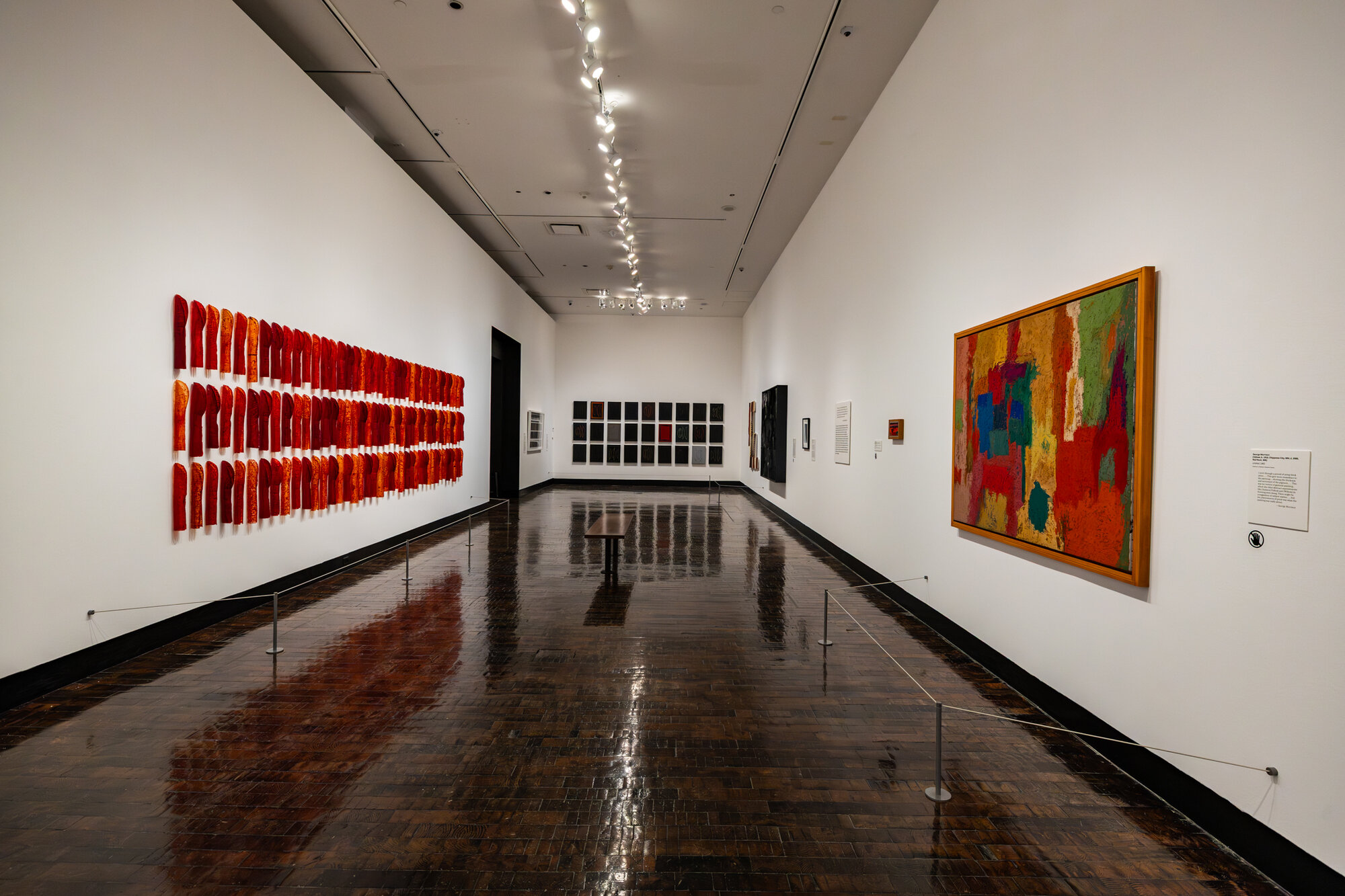 Gallery view of red textile works and framed paintings in "An Indigenous Present" at the Frist Art Museum