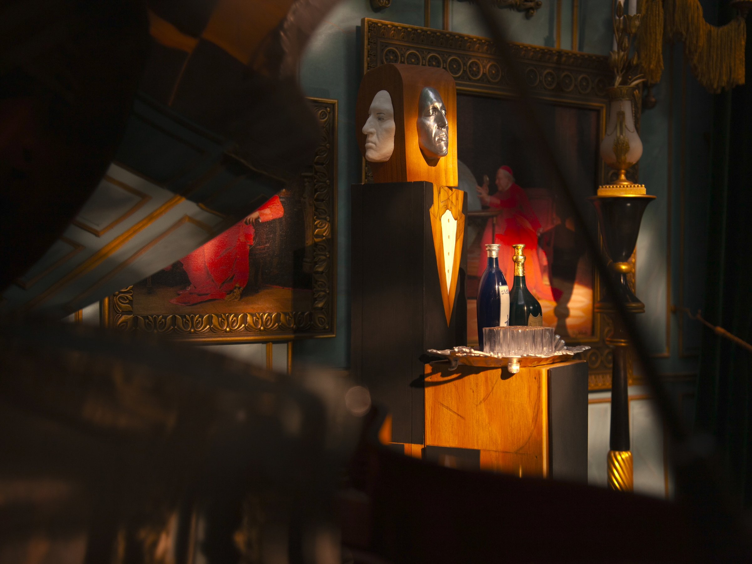 Stop-motion still: a candlelit corner with a masked figure, red shapes and shadowy furniture