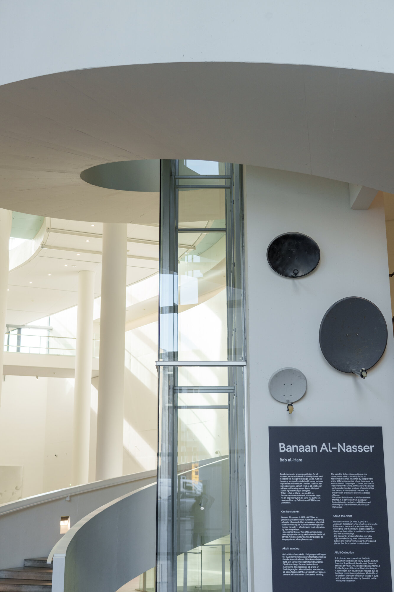 Banaan Al-Nasser's Bab al-Hara installation: three satellite dishes mounted on a museum wall beside a wall text panel