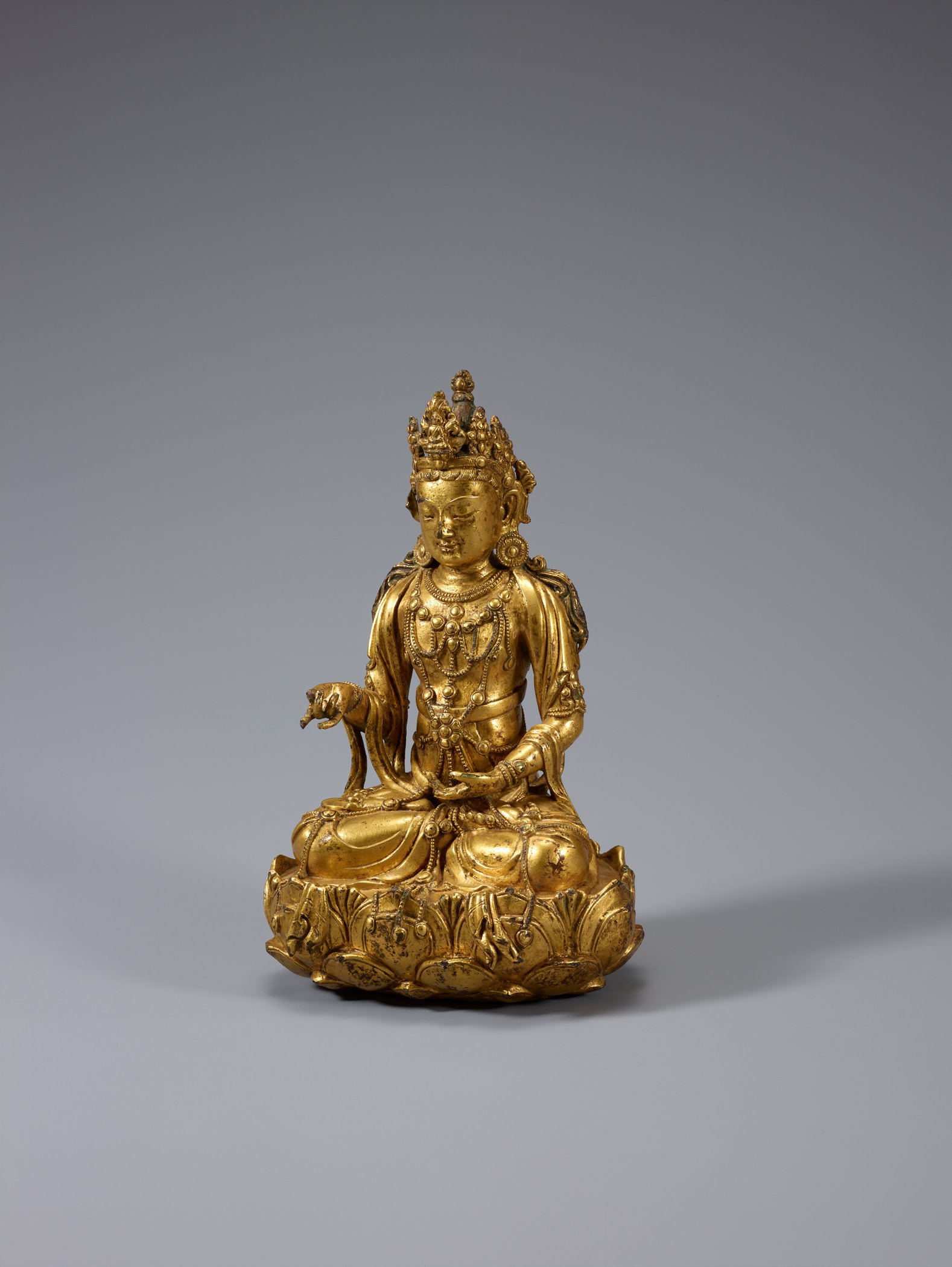 Small gilt bronze seated Avalokitesvara on a lotus base