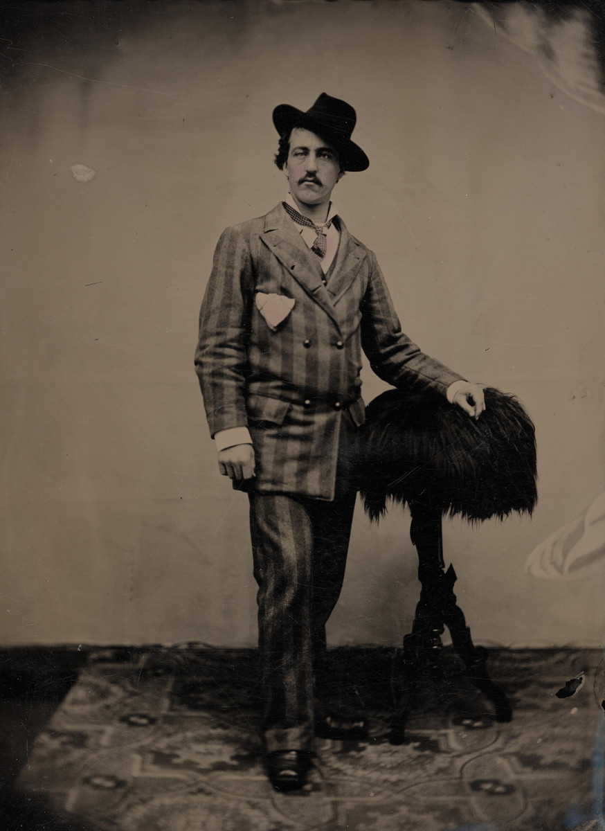 Standing Man in Tilted Hat: a tintype of a man in a checked suit and tilted hat, one hand resting on a fur-covered stand