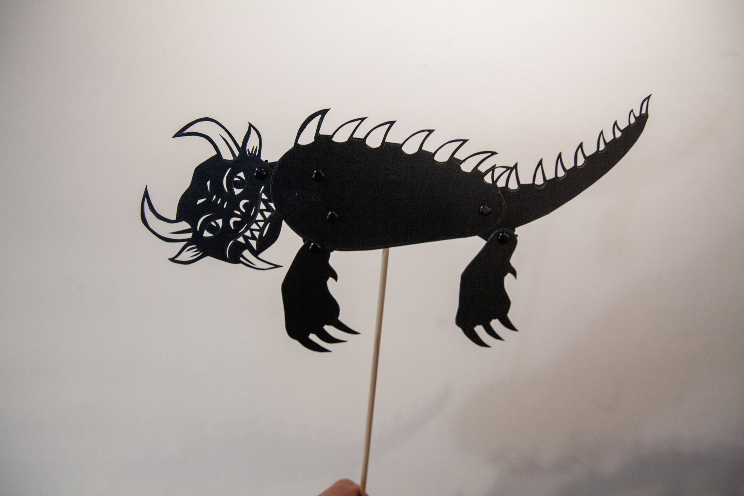 A black shadow-puppet creature on a stick from Erin Kaczkowski’s Of Mound and Myth Shadow Theater