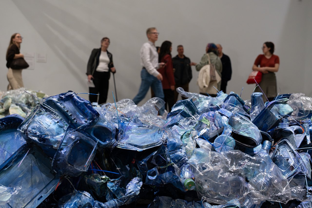Visitors walk past a large installation of crushed blue plastic in Future Geographies