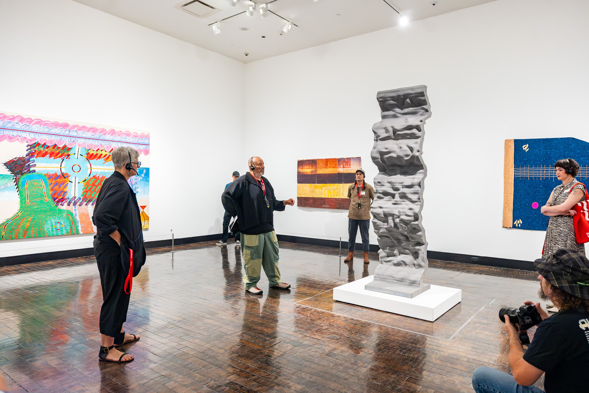 Visitors viewing paintings and a sculptural column in "An Indigenous Present" at the Frist Art Museum