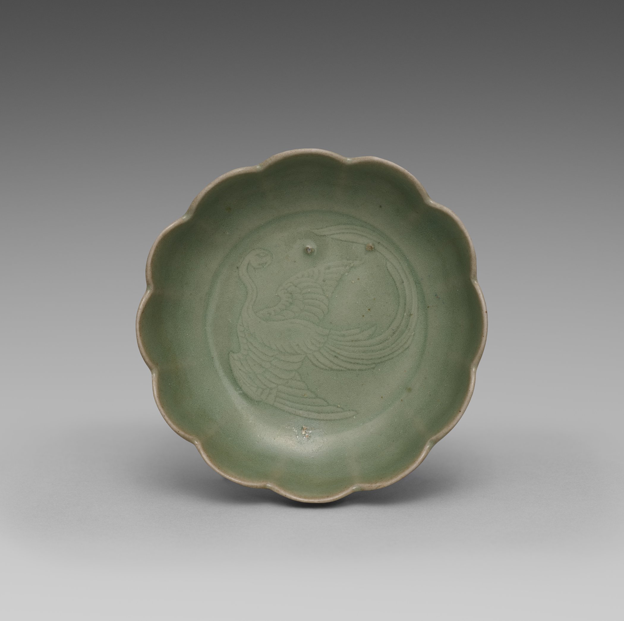 Lobed celadon dish with a molded phoenix design in its well, seen from above