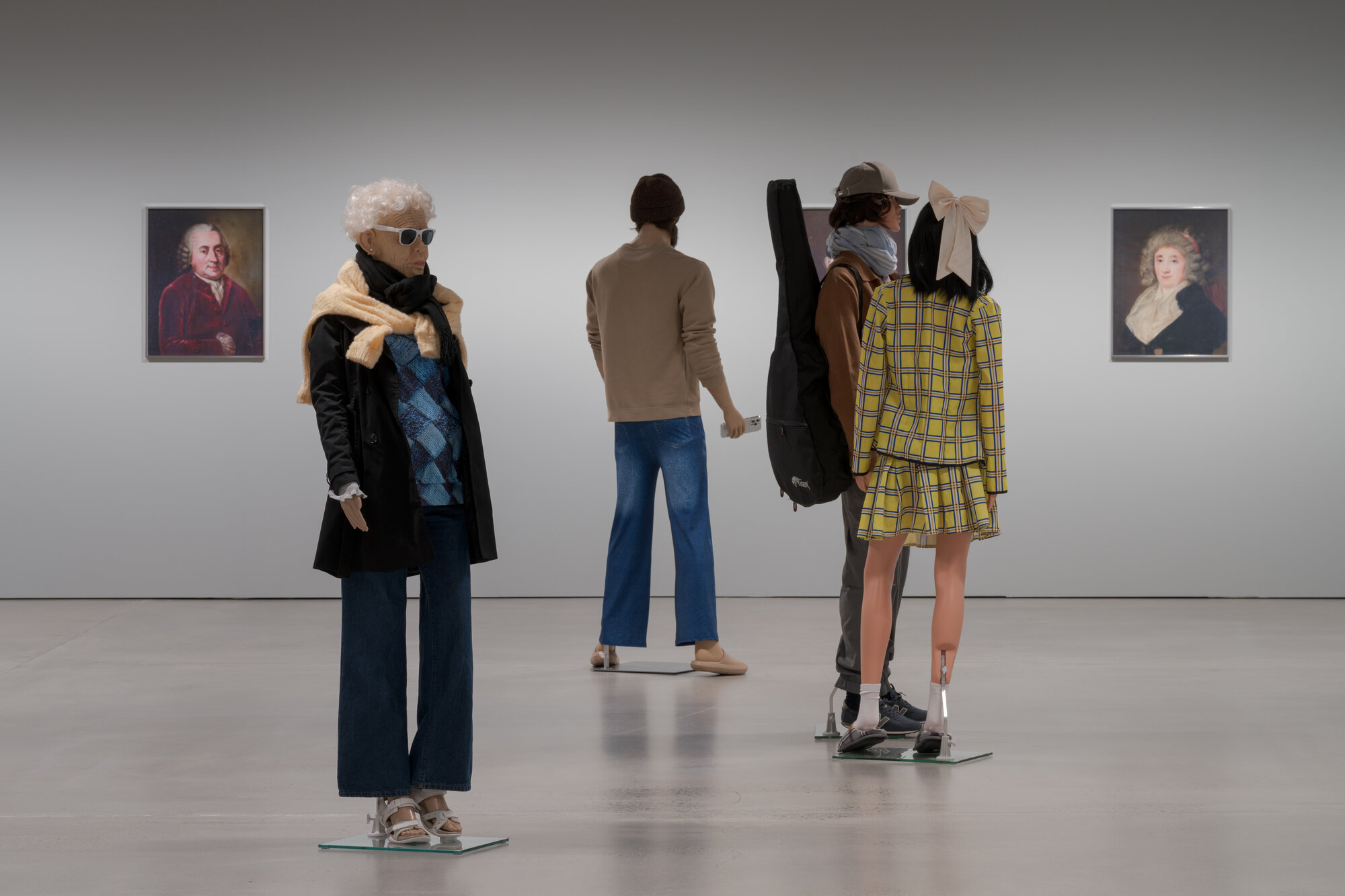 Installation view of "The Populace" at ARoS, mannequins viewed from behind alongside framed portraits