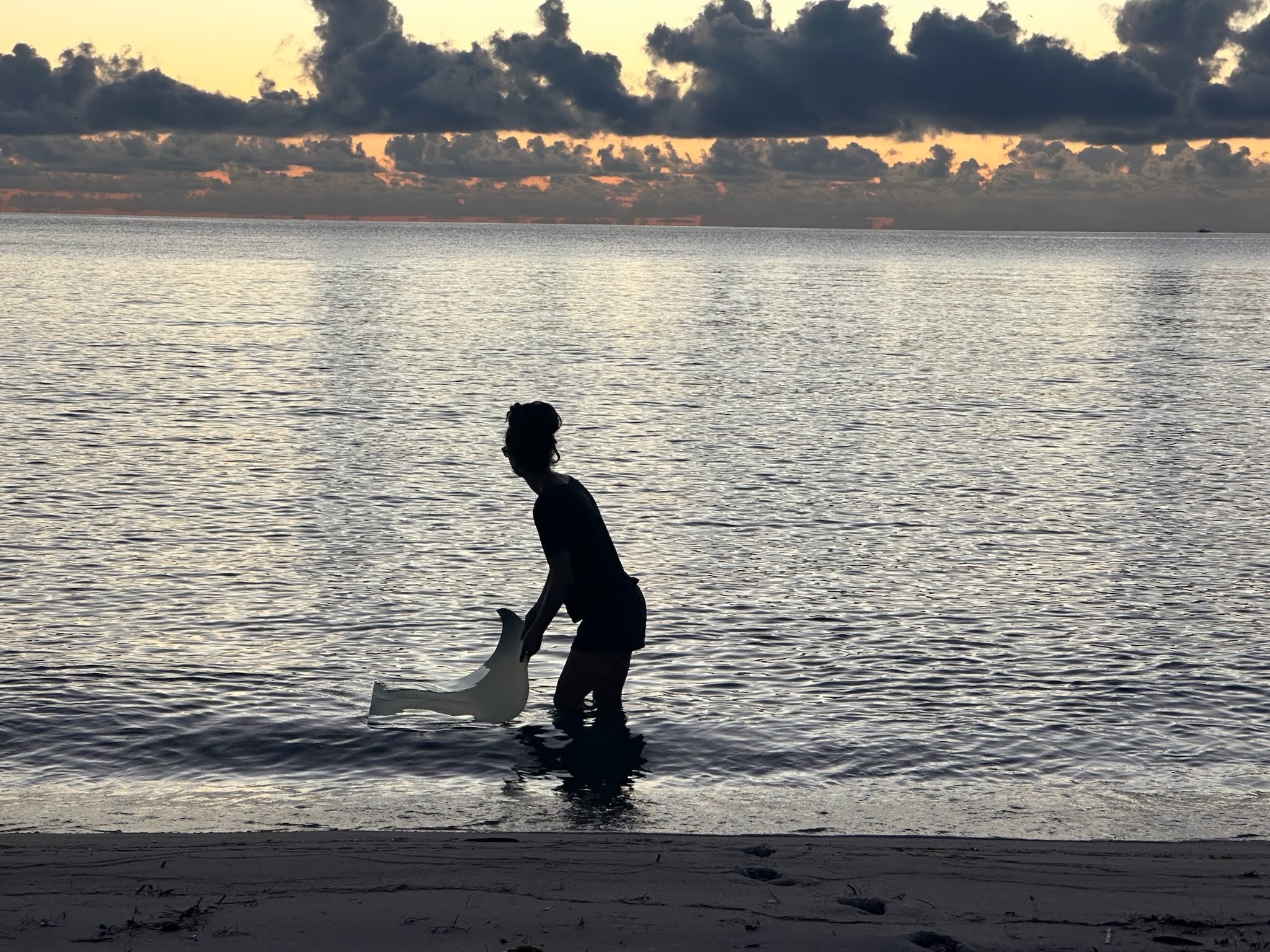 Meghann Riepenhoff silhouetted in shallow water at sunset, printing on Miami Beach
