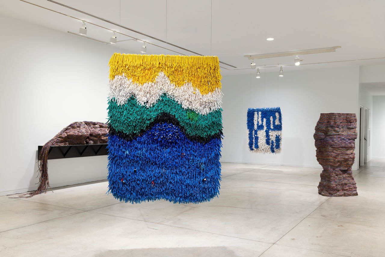 Installation view of Vancouver Now! Emily Hermant, with a hanging cable work in yellow, white, green and blue and a tall cable column