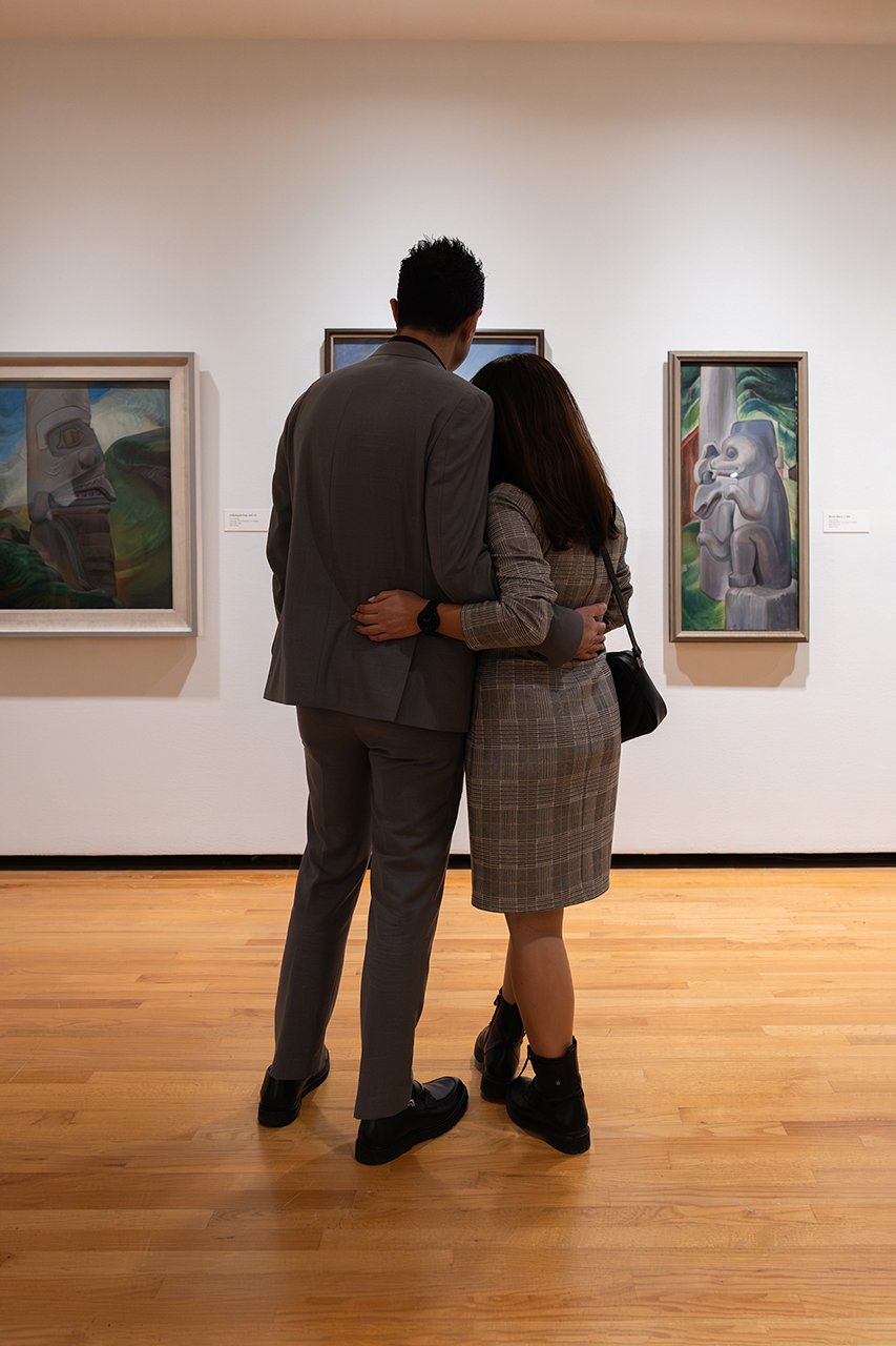 A couple stands before Emily Carr landscapes in That Green Ideal