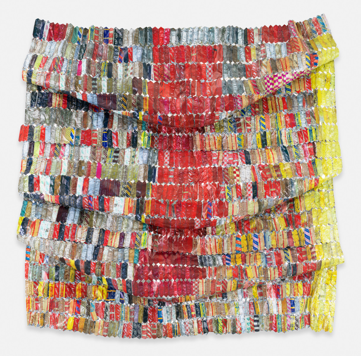 El Anatsui, OG Metal Cloth: a draped wall work of printed aluminum strips in red, white and bright colors joined with copper wire