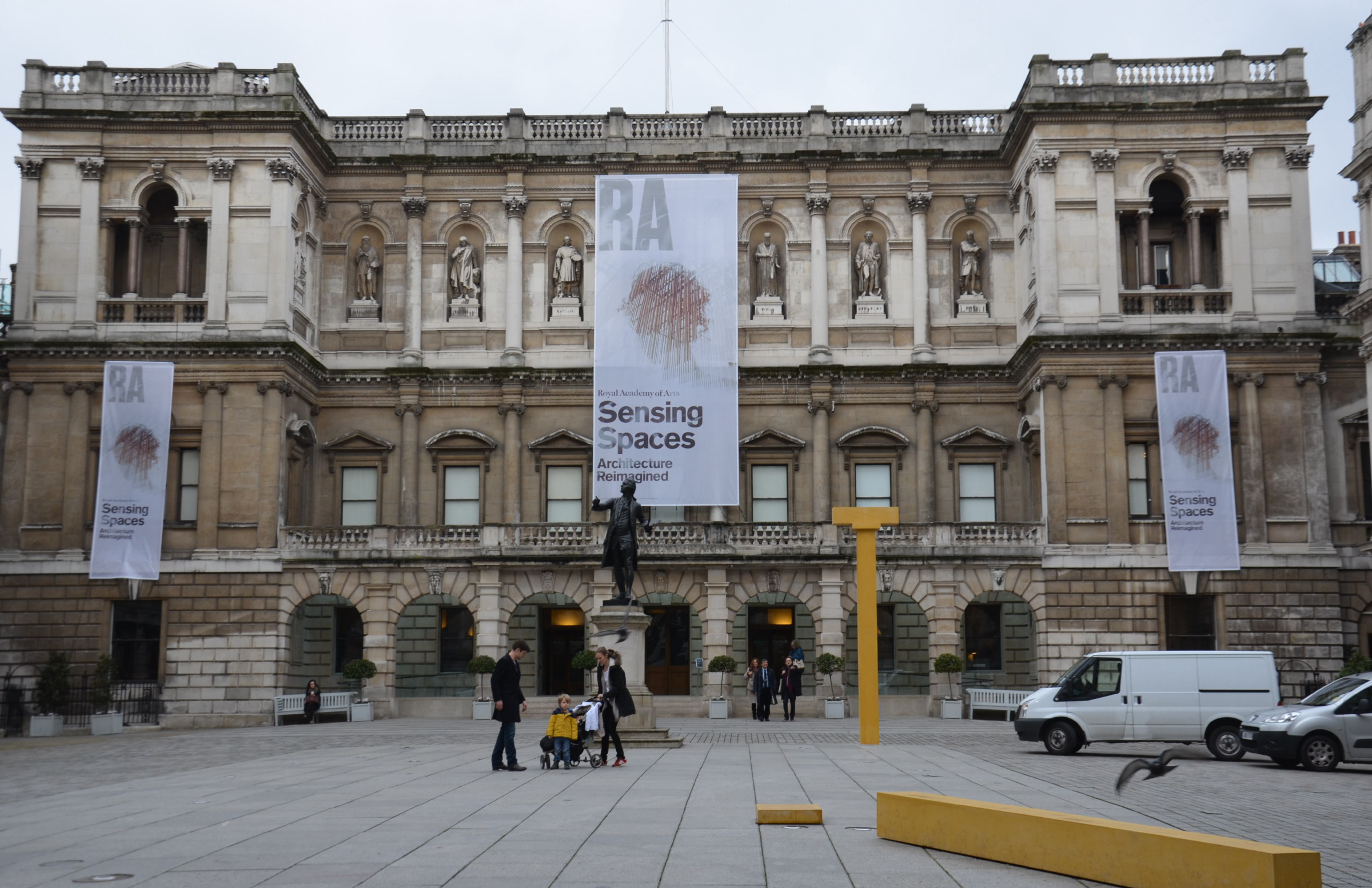 Burlington House on Piccadilly, home of the Royal Academy of Arts: a Palladian stone facade with statues set in niches above the ground-floor arcade, seen across the courtyard.
