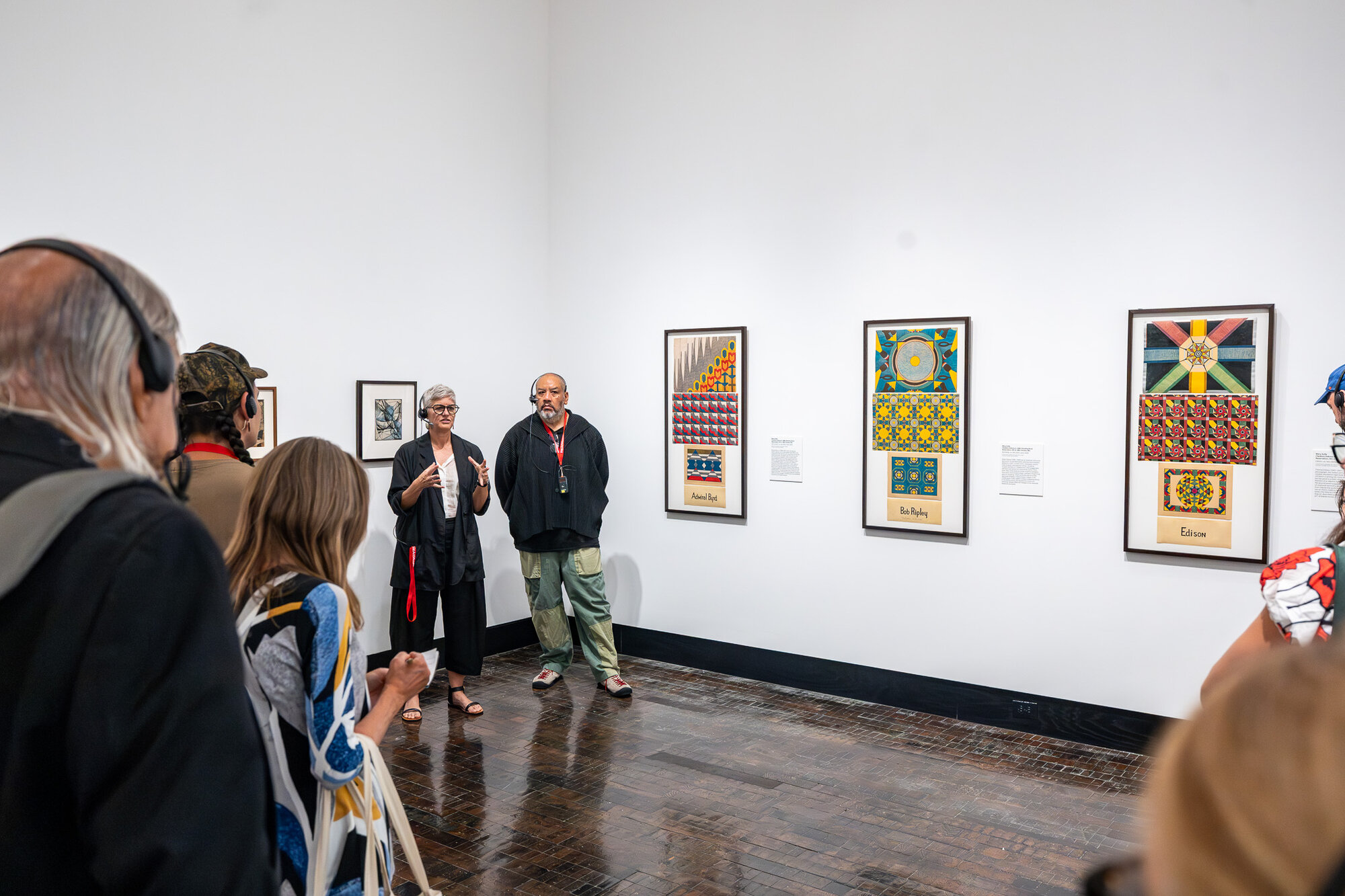 Visitors viewing framed paintings in "An Indigenous Present" at the Frist Art Museum