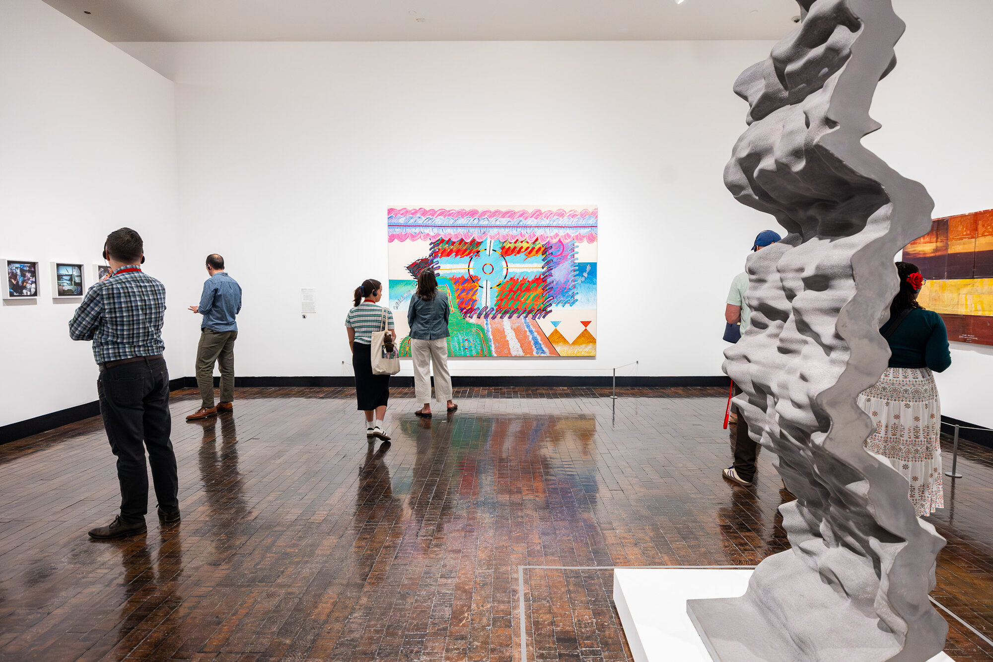 Visitors viewing a sculptural column and paintings in "An Indigenous Present" at the Frist Art Museum